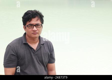 Ein junger asiatischer Mann mit Brille blickt direkt auf die Kamera Stockfoto