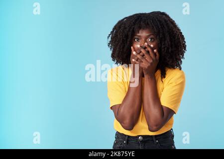 Das Leben änderte sich in einem Moment. Studioaufnahme einer attraktiven jungen Frau, die schockiert vor blauem Hintergrund aussieht. Stockfoto