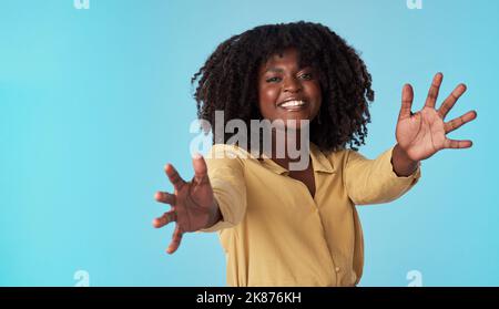 Meine Arme waren zum Umarmen gemacht. Studioaufnahme einer attraktiven jungen Frau, die ihre Arme vor blauem Hintergrund ausstreckt. Stockfoto