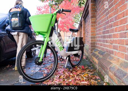 Lime Mikromobilitätsfahrrad mit grünem Korb vor dem Fahrrad, Parks in Pflaster mit bunten Herbstbaum Blätter London England Großbritannien Stockfoto