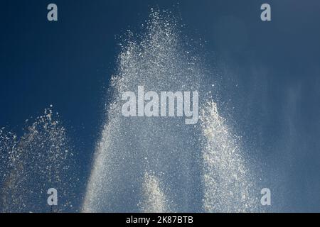 Wasserstrahlen gegen den Himmel. Brunnen in der Stadt. Details des Brunnens auf der Straße. Spritztropfen. Stockfoto