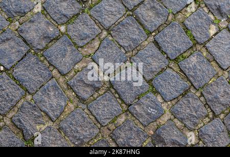 Struktur einer gepflasterten Straße. Muster der alten Allee. Gerade Reihen von Steinen. Stockfoto