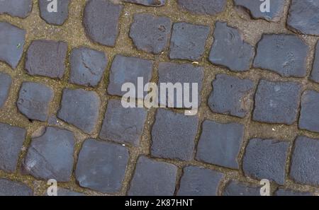 Struktur einer gepflasterten Straße. Muster der alten Allee. Gerade Reihen von Steinen. Stockfoto