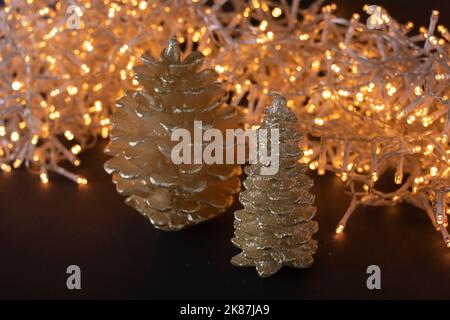 Dekorative Kerzen in Form eines Weihnachtsbaums und eines Kegels mit goldenen Lichtern auf dem Hintergrund Stockfoto
