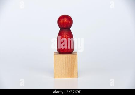 Rote Holzfiguren auf einem Holzwürfel. Einsames Konzept. Stockfoto