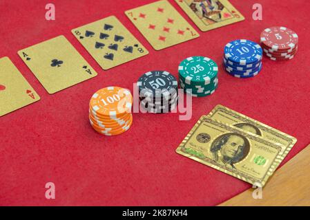 Texas Holden Poker Tisch mit goldenen Spielkarten und im Format eines 100-Dollar-Scheines neben den Wettchips. Poker und Black Jack sind sehr Pop Stockfoto