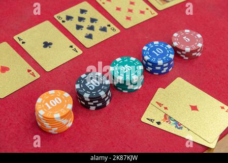 Texas Holden Poker Tisch mit goldenen Spielkarten und im Format eines 100-Dollar-Scheines neben den Wettchips. Poker und Black Jack sind sehr Pop Stockfoto