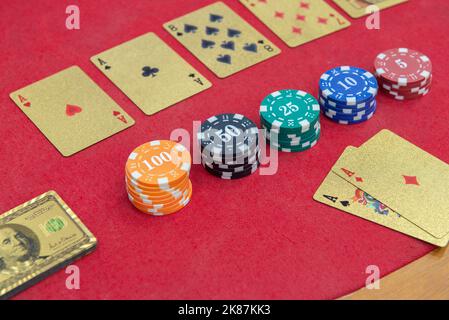Texas Holden Poker Tisch mit goldenen Spielkarten und im Format eines 100-Dollar-Scheines neben den Wettchips. Poker und Black Jack sind sehr Pop Stockfoto