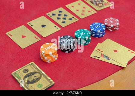 Texas Holden Poker Tisch mit goldenen Spielkarten und im Format eines 100-Dollar-Scheines neben den Wettchips. Poker und Black Jack sind sehr Pop Stockfoto