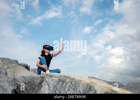 Frau mit einem VR-Headset, das in den Himmel reicht. Stockfoto