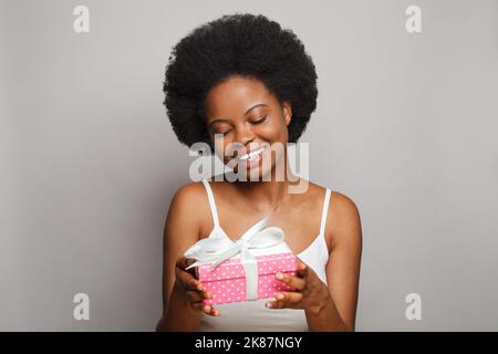 Ziemlich attraktive Frau hält rosa Geschenk mit weißem Seidenband, Studio-Porträt Stockfoto