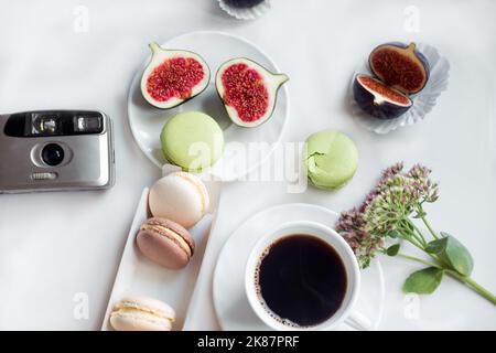 Ästhetische Filmkamera Flatlay, Tassen Kaffee, Feigen und Makronen auf weißem Hintergrund, Draufsicht Stockfoto