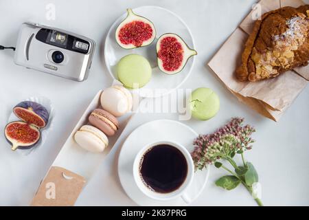 Ästhetische Filmkamera Flatlay, Tassen Kaffee, Feigen und Makronen auf weißem Hintergrund, Draufsicht Stockfoto