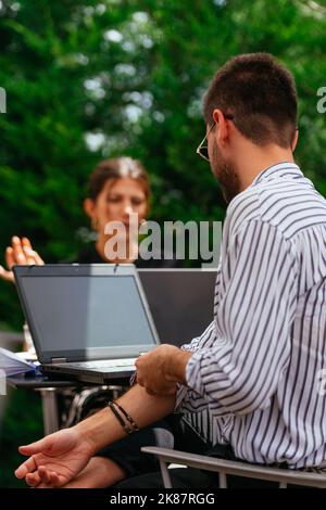 Zwei junge Geschäftsleute unterhalten sich ernsthaft über ihr Projekt. Sie arbeiten online Stockfoto