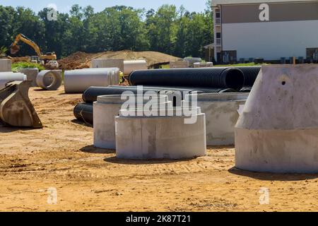 Auf der Baustelle wurden großflächige Zement-Abwasserbetonbrunnen installiert, um Entwässerungssysteme für Industriegebäude zu schaffen. Stockfoto