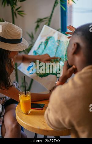 Männliche und weibliche multirassische Touristen suchen auf der Karte nach einem Ziel, während sie in einer Café-Bar sitzen Stockfoto