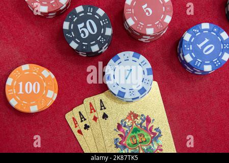 Vier Asse in der Nähe von Chips auf einem roten Filztisch. Poker-Spiel ist eines der beliebtesten Kartenspiele der Welt und spielte viel in Casinos. Karte Stockfoto