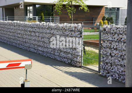 Automatisches Eingangstor in Kombination mit einer Wand aus Gabion. Stockfoto