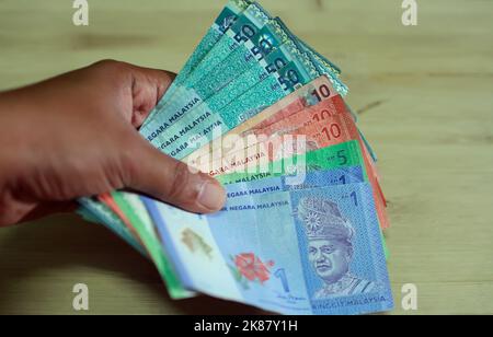 Ein Mann, der viele malaysische, bunte Banknoten in aufsteigender Reihenfolge hält Stockfoto