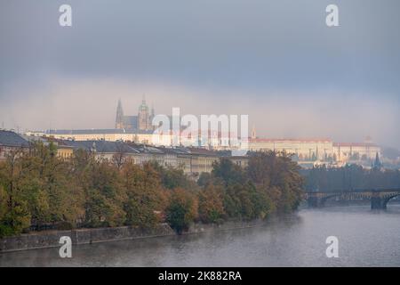 Panorama der Prager Burg in Prag von der Jiráskův-Brücke aus an einem nebligen Herbstmorgen. Die Insel Dětský ostrov liegt auf der linken Seite. Stockfoto