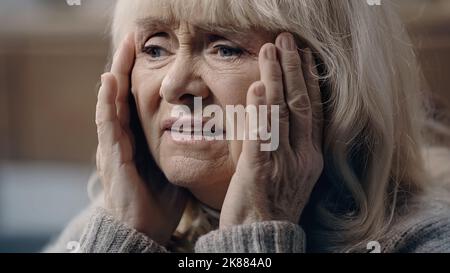 Ältere Frau mit Demenz, die an Kopfschmerzen und Kopfberühre leidet Stockfoto