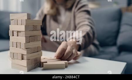 Beschnittene Ansicht einer älteren Frau mit Demenz, die in einem Blockholzspiel spielt Stockfoto