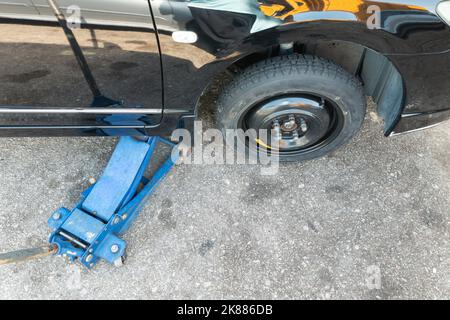 Hydraulischer Wagenheber zum Austausch von Reifenpannenreifen durch temporären Ersatzreifen Stockfoto