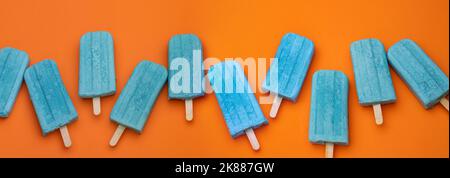 Einige blaue Eiszapfen auf einem orangefarbenen Hintergrund für Banner, Panorama, Rand Stockfoto