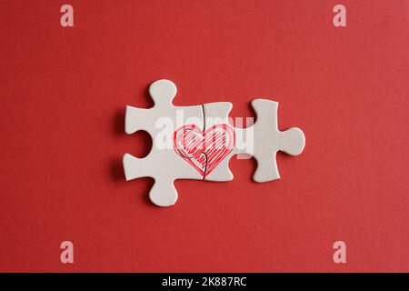 Draufsicht Bild der verbundenen Puzzle-Stücke mit rotem Herz-Symbol auf rotem Hintergrund. Liebe und Beziehung Konzept Stockfoto
