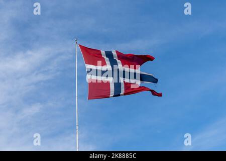 Eine winkende norwegische Schwalbenschwanzfahne mit blauem Himmel im Hintergrund. Stockfoto