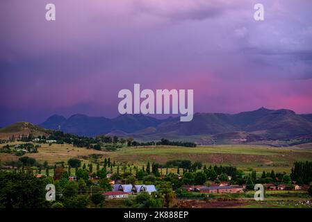 Ein Blick auf die Berge unter einem stürmischen purpurnen Himmel bei Sonnenuntergang in Clarens, Südafrika. Die beliebte Stadt liegt in der Nähe des Golden Gate Highlands National Park Stockfoto