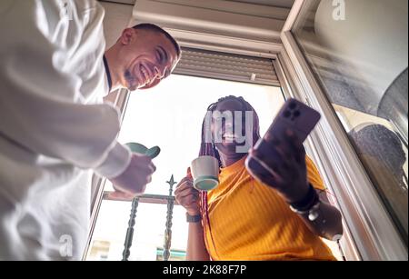 Glückliches multiethnisches Paar, das zu Hause Kaffee trinken kann Stockfoto