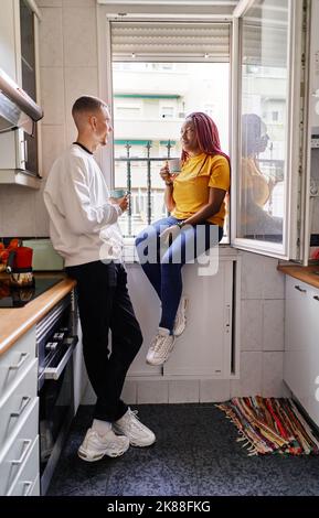 Glückliches multiethnisches Paar, das zu Hause Kaffee trinken kann Stockfoto