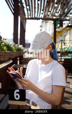 Ein Teenager mit blauen Haaren in einem Café wartet auf eine Bestellung Stockfoto