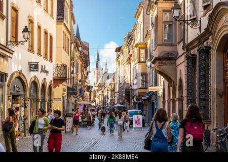 Touristen und einheimische Franzosen genießen die Geschäfte und Cafés in einer Straße aus halbhölzernen Gebäuden im mittelalterlichen Straßburg Frankreich. Stockfoto