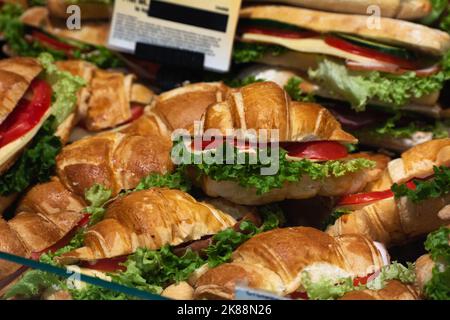Sandwich-Croissant mit Käse, Tomaten und Salat auf einer Supermarktvitrine Stockfoto