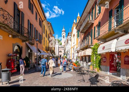 Eine farbenfrohe, enge Straße mit Geschäften und Cafés in der mittelalterlichen Altstadt von Menaggio, Italien, am Ufer des Comer Sees. Stockfoto