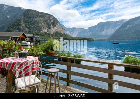 Ein kleiner Tisch in einem Café im Freien mit Blick auf den See und die Alpen in der österreichischen Bergstadt Hallstatt. Stockfoto