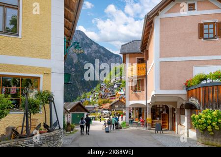 Eine malerische Straße mit Geschäften und Cafés durch das mittelalterliche Dorf Hallstatt, Österreich, am Ufer des Hallstatt-Sees in Österreichs Alpen Stockfoto