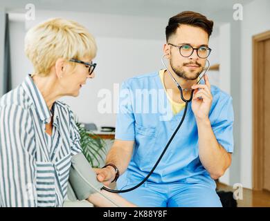 Krankenschwester Arzt Senior care Betreuer Hilfe überprüfen Untersuchung Blutdruck überprüfen Puls Ruhestand Haus Stethoskop Pflege ältere Mann Frau Gesundheit Stockfoto