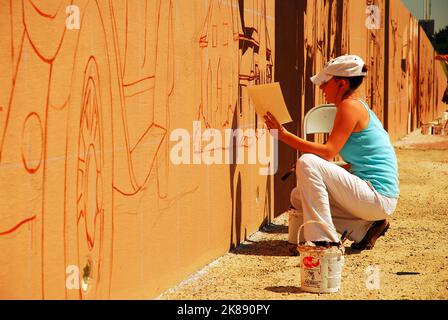 Eine junge Frau malt ein Wandgemälde an den Wänden am Rande der Interstate 35 in der Nähe von Denton Texas, das Kunst für den Weg zum Arbeitsweg bringt Stockfoto