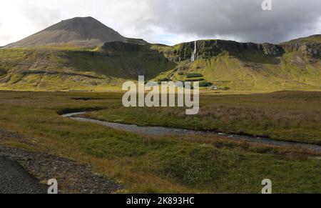 Der Bjarnarfoss Wasserfall mit dem Vulkan Mælifell, der im Westen aufragt. Gedreht auf der Halbinsel Snæfellsnes im Westen Islands. Stockfoto