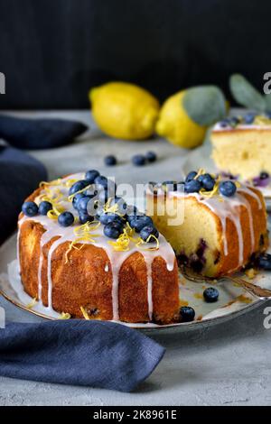 Zitrone Blaubeerkuchen mit süßem Zuckerguss und Beeren bedeckt Stockfoto