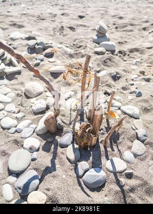 Pyramide mit Steinen und Treibholz am Kiesstrand gebaut. Urlaub am Meer. Die Natur in der Kindheit erkunden. Stockfoto