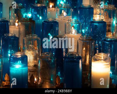 Mehrere türkisfarbene und klare Glasbehälter mit vielen brennenden Votivkerzen in der Notre-Dame-Basilika in Old Montreal, Quebec. Stockfoto