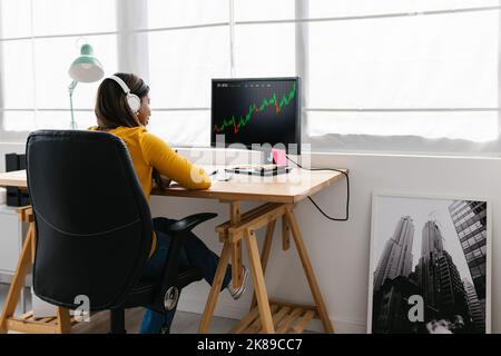 Junge Erwachsene Frau, die zu Hause Aktienmarktdaten studiert Stockfoto