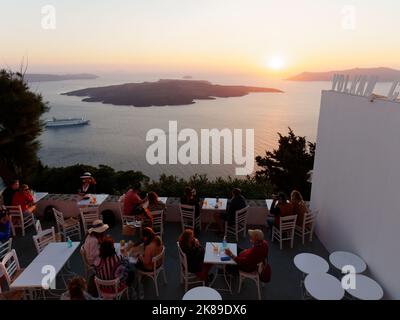 Restaurant mit Blick auf die Caldera, einschließlich eines Kreuzfahrtschiffs bei Sonnenuntergang in Santorin, einer griechischen Ägäischen Insel. Stockfoto