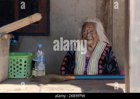 Eine Hmong-Frau sah vor ihrem Haus im ländlichen Chiang Mai sitzen. Die Lahu- und Hmong-Gemeinschaften sind zwei der ethnischen Minderheiten, die in Thailand als „Bergstämme“ eingestuft werden. Ursprünglich aus Tibet und China stammend, leben sie in Dörfern in den bergigen nördlichen Provinzen Chiang Mai und Chiang Rai. Stockfoto