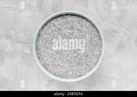 Über Nacht Chia-Samenpudding in der Schüssel. Draufsicht, Kopierbereich. Frühstück, Superfood und veganes Food-Konzept. Grauer Hintergrund Stockfoto