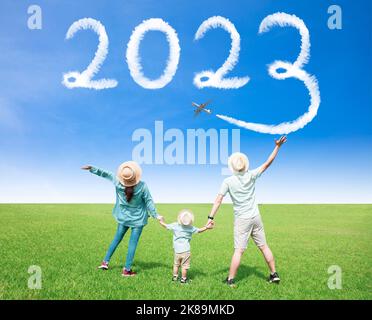 Frohes neues Jahr 2023 Konzept. Glückliche Familie, die die Wolken mit dem Flugzeug in den Himmel zieht Stockfoto